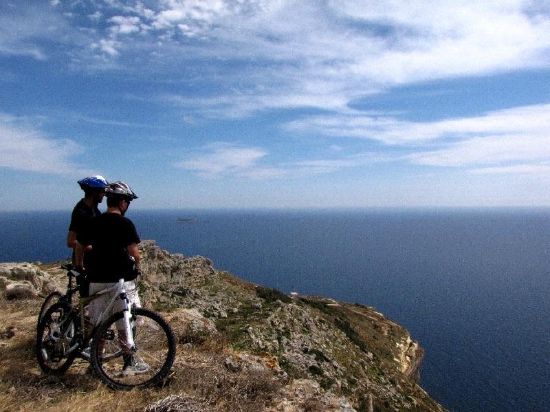 Two cyclists pausing on the clifftops to look out over the sea
